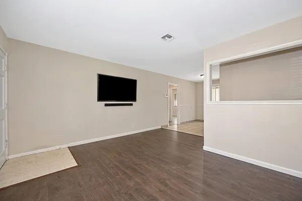 a view of an empty room with wooden floor and windows