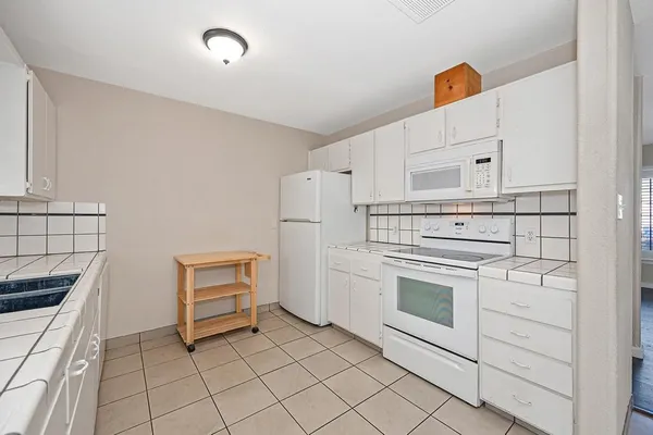 a kitchen with white cabinets and white appliances