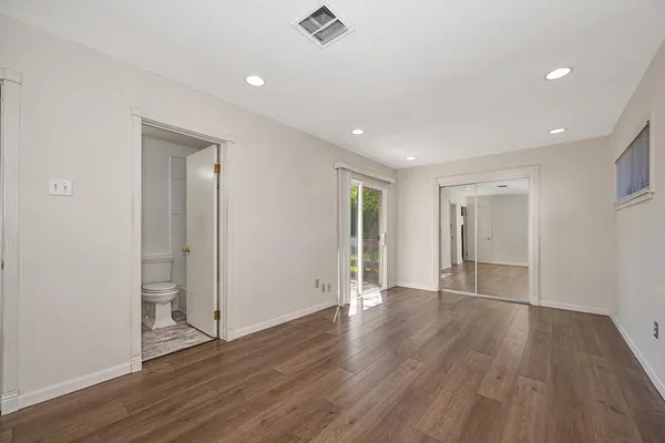 a view of an empty room with wooden floor and closet