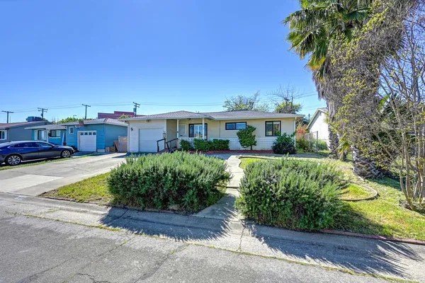 a front view of a house with a yard and potted plants