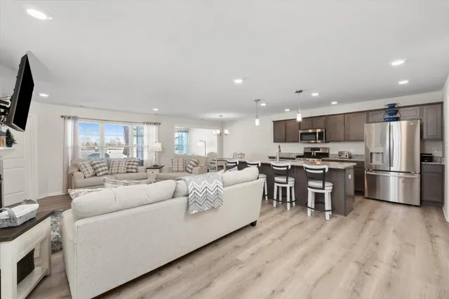 a living room with stainless steel appliances furniture and a kitchen view