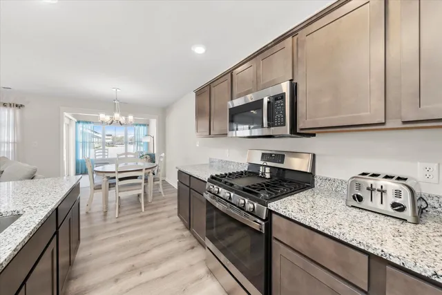 a kitchen with granite countertop kitchen island stainless steel appliances a stove sink microwave and cabinets