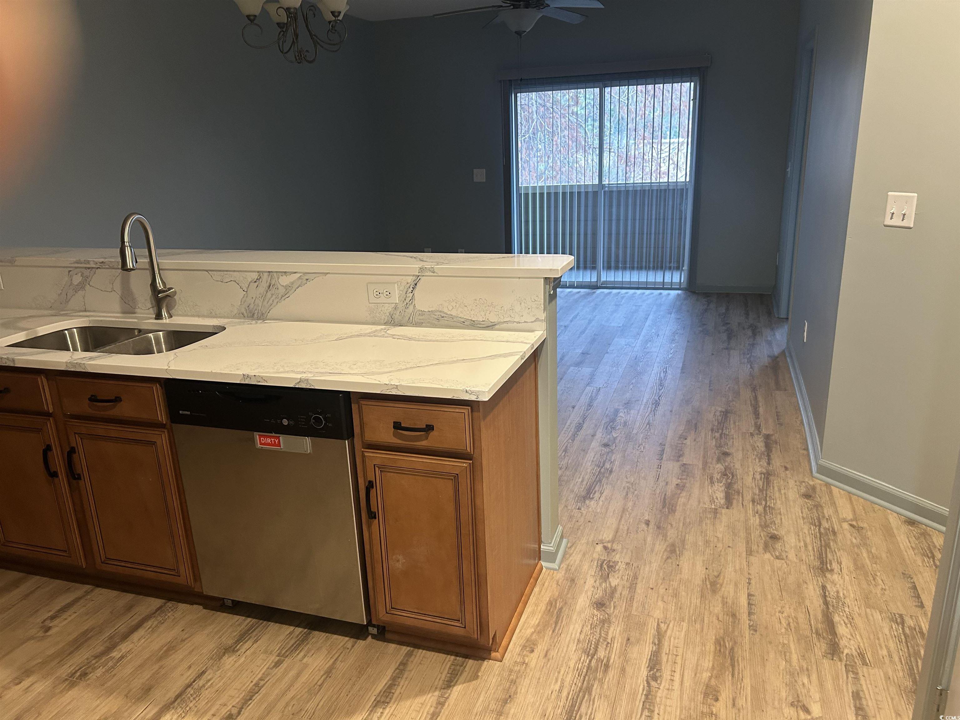 4104 Pinehurst Circle, Unit 2G Little River, SC 29566 - Photo 3 of 17 Kitchen with brown cabinets, stainless steel dishwasher, light wood finished floors, and light stone countertops