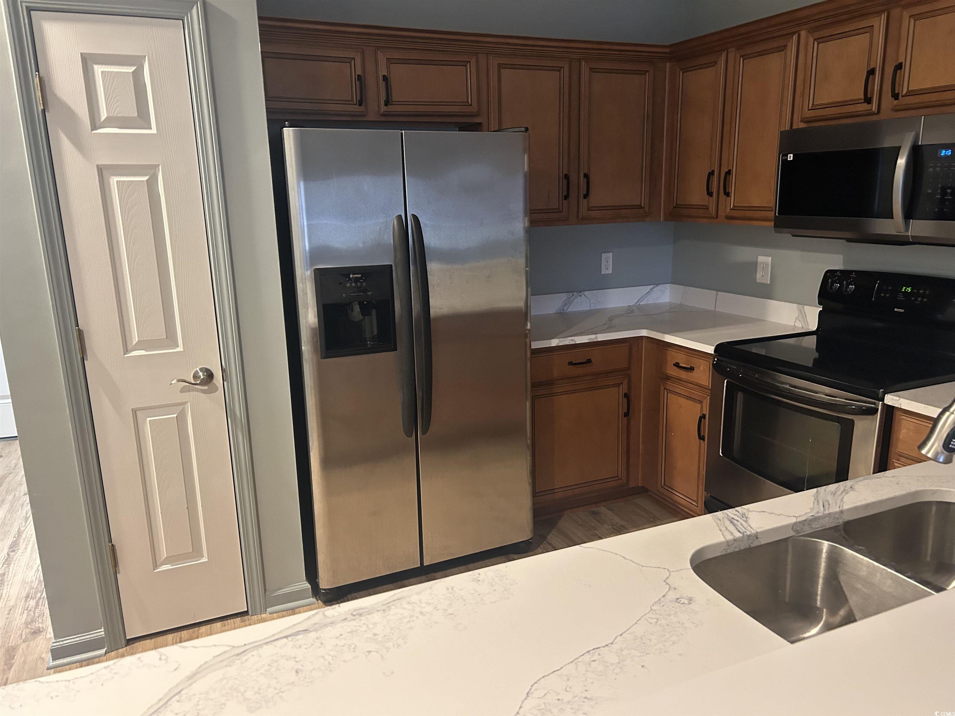 4104 Pinehurst Circle, Unit 2G Little River, SC 29566 - Photo 5 of 17 Kitchen with stainless steel appliances, brown cabinets, light stone counters, and light wood-style flooring