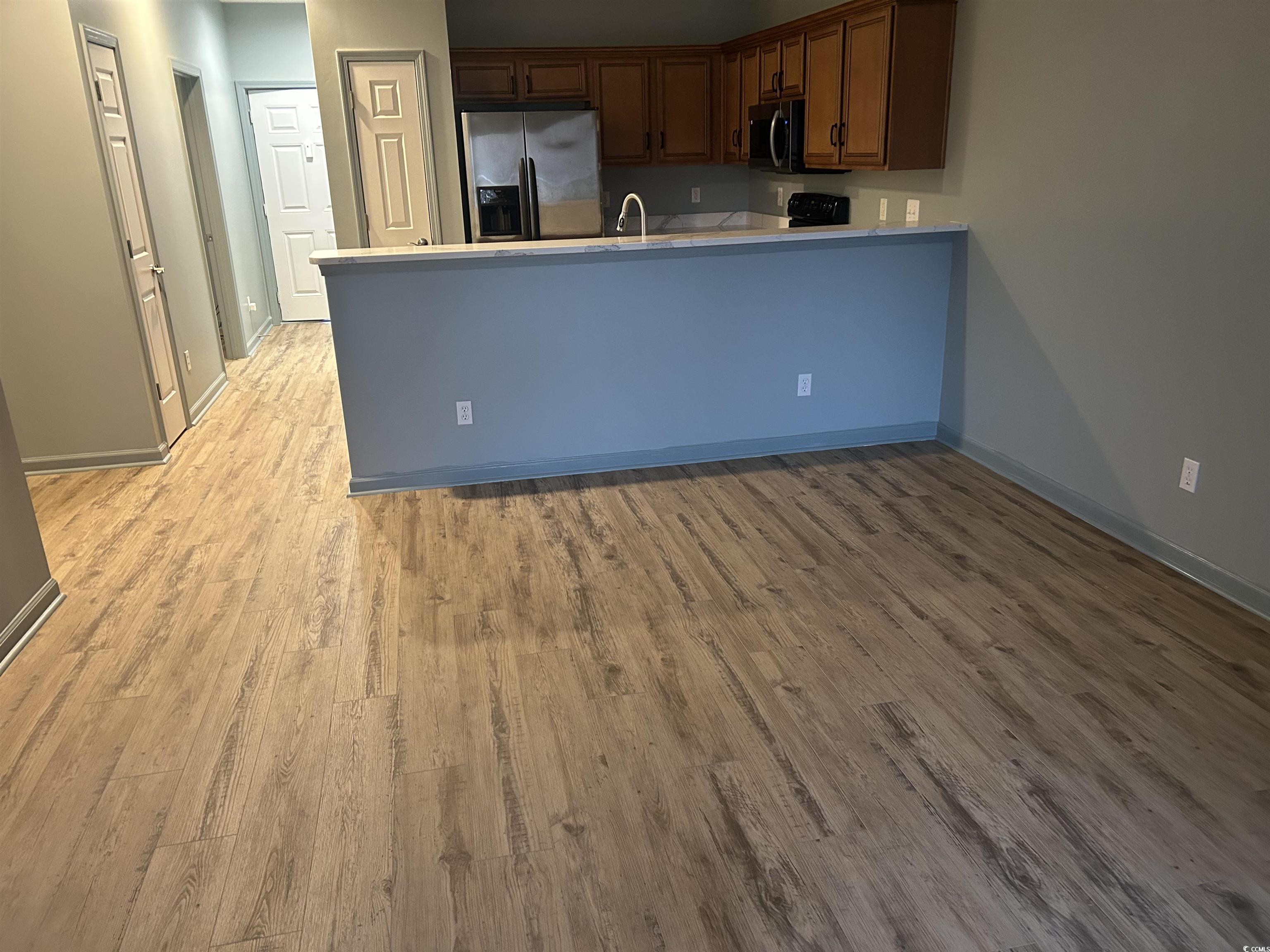 4104 Pinehurst Circle, Unit 2G Little River, SC 29566 - Photo 10 of 17 Kitchen with appliances with stainless steel finishes, a peninsula, light countertops, light wood finished floors, and brown cabinets