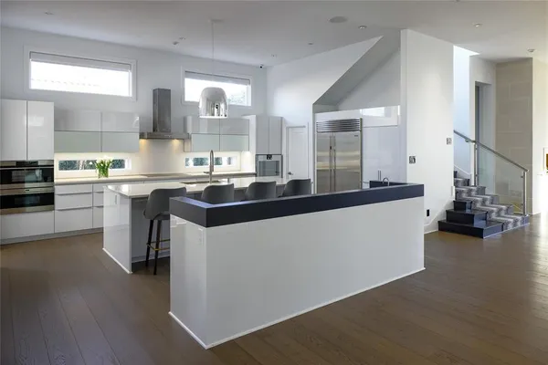 a kitchen with a sink and chairs with wooden floors