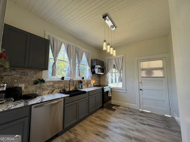 a kitchen with granite countertop a sink cabinets and wooden floor