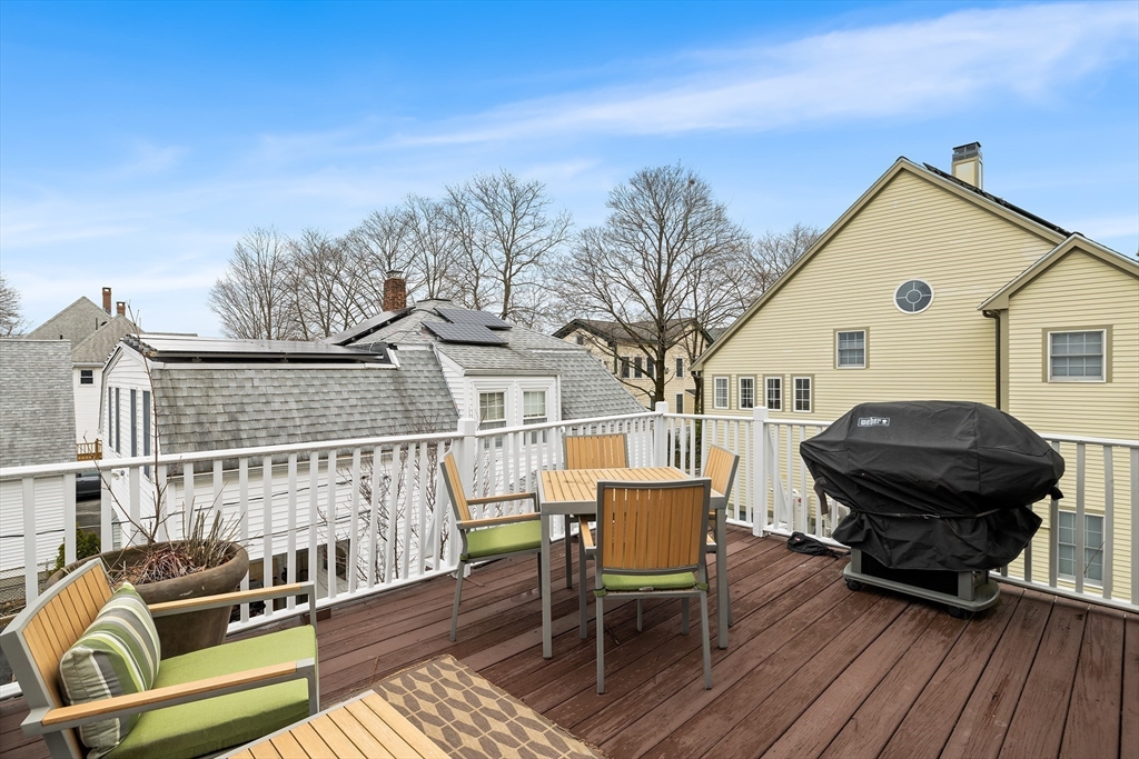 405 Cherry Street, Unit 2 Newton, MA 02465 - Photo 34 of 39 a view of a roof deck with table and chairs a barbeque with wooden floor and fence