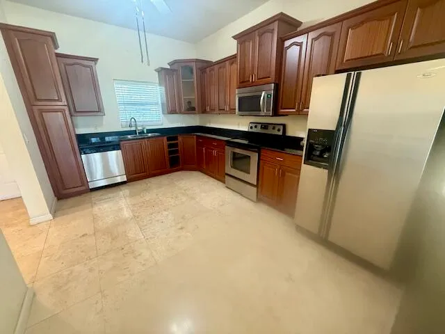 a kitchen with stainless steel appliances granite countertop a refrigerator a stove top oven a sink and dishwasher