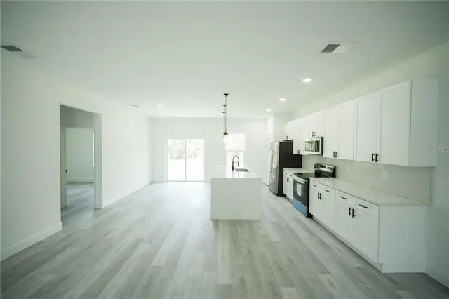 a large kitchen with cabinets wooden floor and a sink