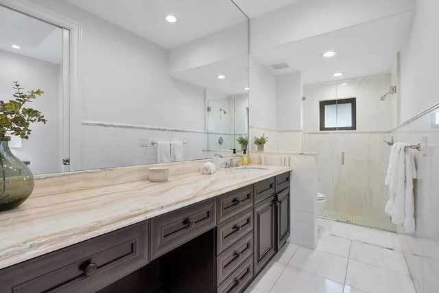 a bathroom with a granite countertop toilet a sink a mirror a window and vanity