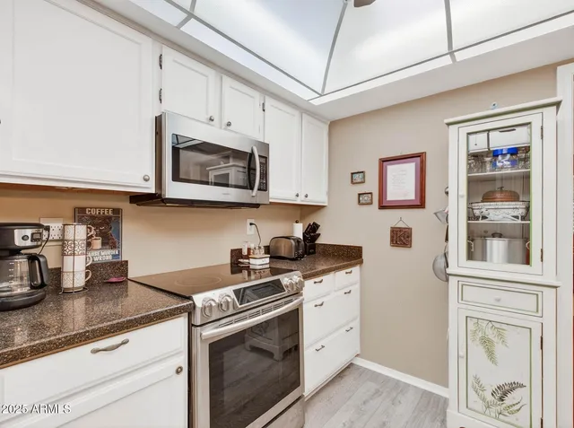 a kitchen with stainless steel appliances granite countertop white cabinets stove top oven and sink