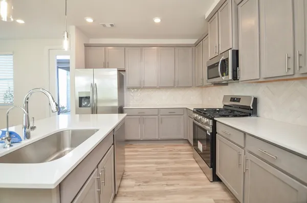 a kitchen with a sink dishwasher a refrigerator with white cabinets and wooden floor