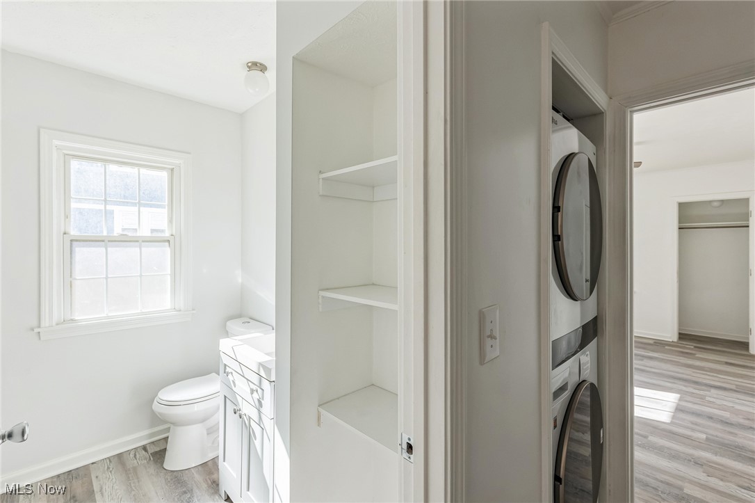 Bathroom with vanity, toilet, hardwood / wood-style flooring, and stacked washing maching and dryer