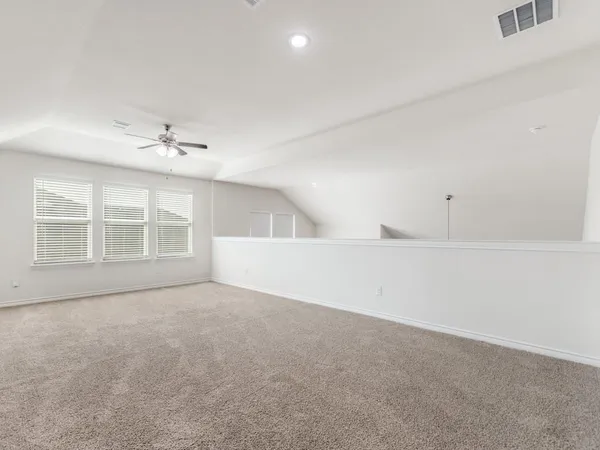 an empty room with windows and fan