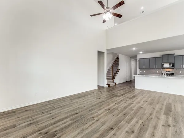a large white kitchen with wooden floor and a sink