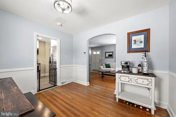 a view of a kitchen and an empty room with wooden floor