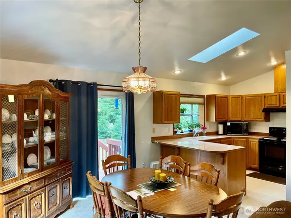 a kitchen with stainless steel appliances granite countertop a stove a refrigerator a kitchen island a dining table and chairs with wooden floor