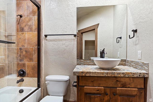 246 Woods Creek Road Morgan, UT 84050 - Photo 64 of 69 Bathroom featuring a vessel sink, wood vanity, stone countertop, tiled backsplash, and a tiled shower with a glass enclosure