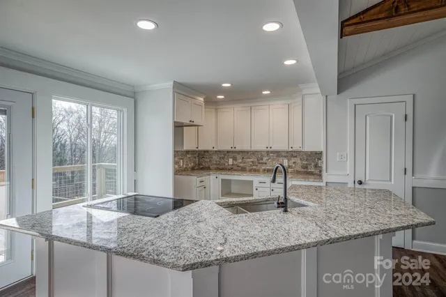 a kitchen with kitchen island granite countertop a sink and a stove