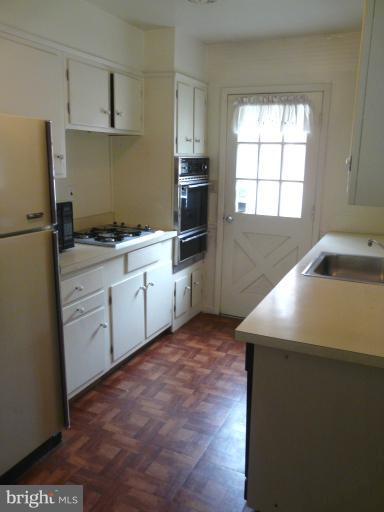 705 Stirling Road Silver Spring, MD 20901 - Photo 14 of 23 a kitchen with white cabinets and white appliances