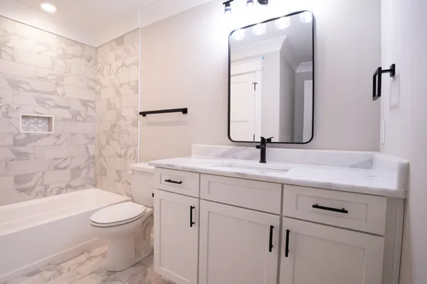 a bathroom with a bathtub shower sink vanity and toilet