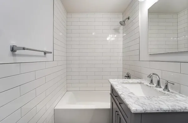 a bathroom with a granite countertop sink and a bathtub