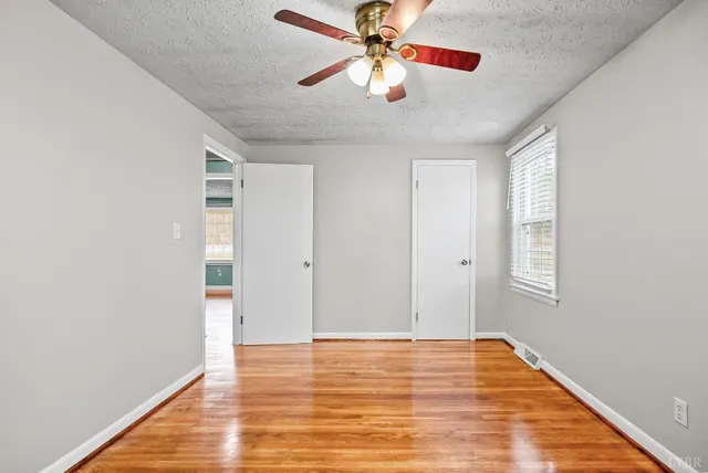 a view of an empty room with window and wooden floor