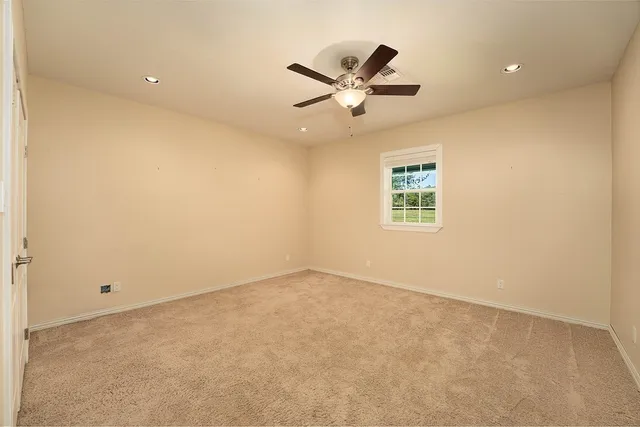 an empty room with windows and ceiling fan