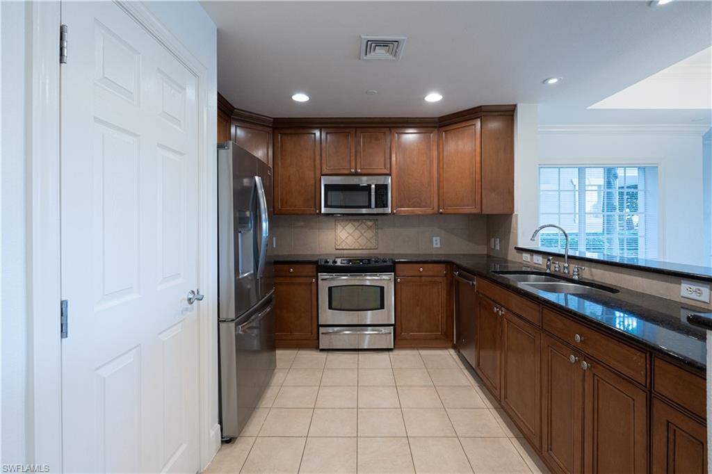 1362 Centre Ct Ridge Drive, Unit 101 Reunion, FL 34747 - Photo 5 of 25 Kitchen featuring crown molding, stainless steel appliances, backsplash, sink, and light tile floors