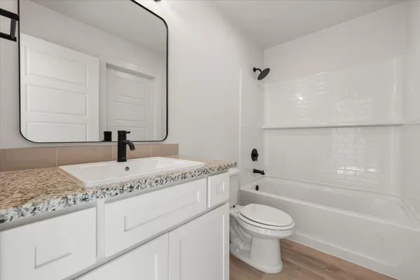 a bathroom with a granite countertop sink toilet a mirror and bathtub
