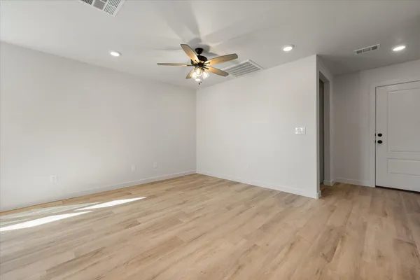 an empty room with wooden floor fan and windows