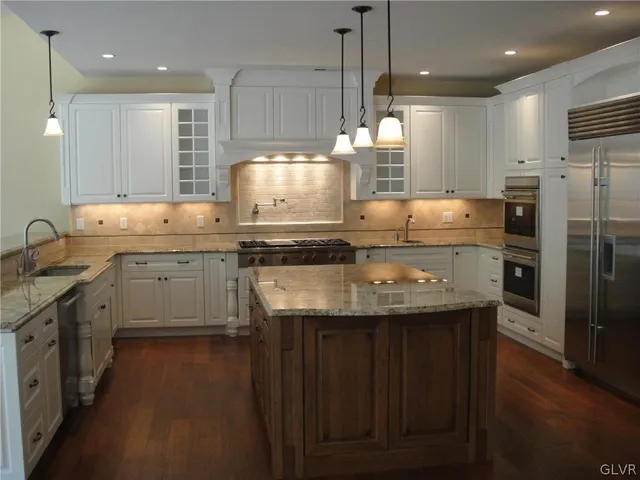 a kitchen with stainless steel appliances granite countertop a sink a stove a refrigerator and island