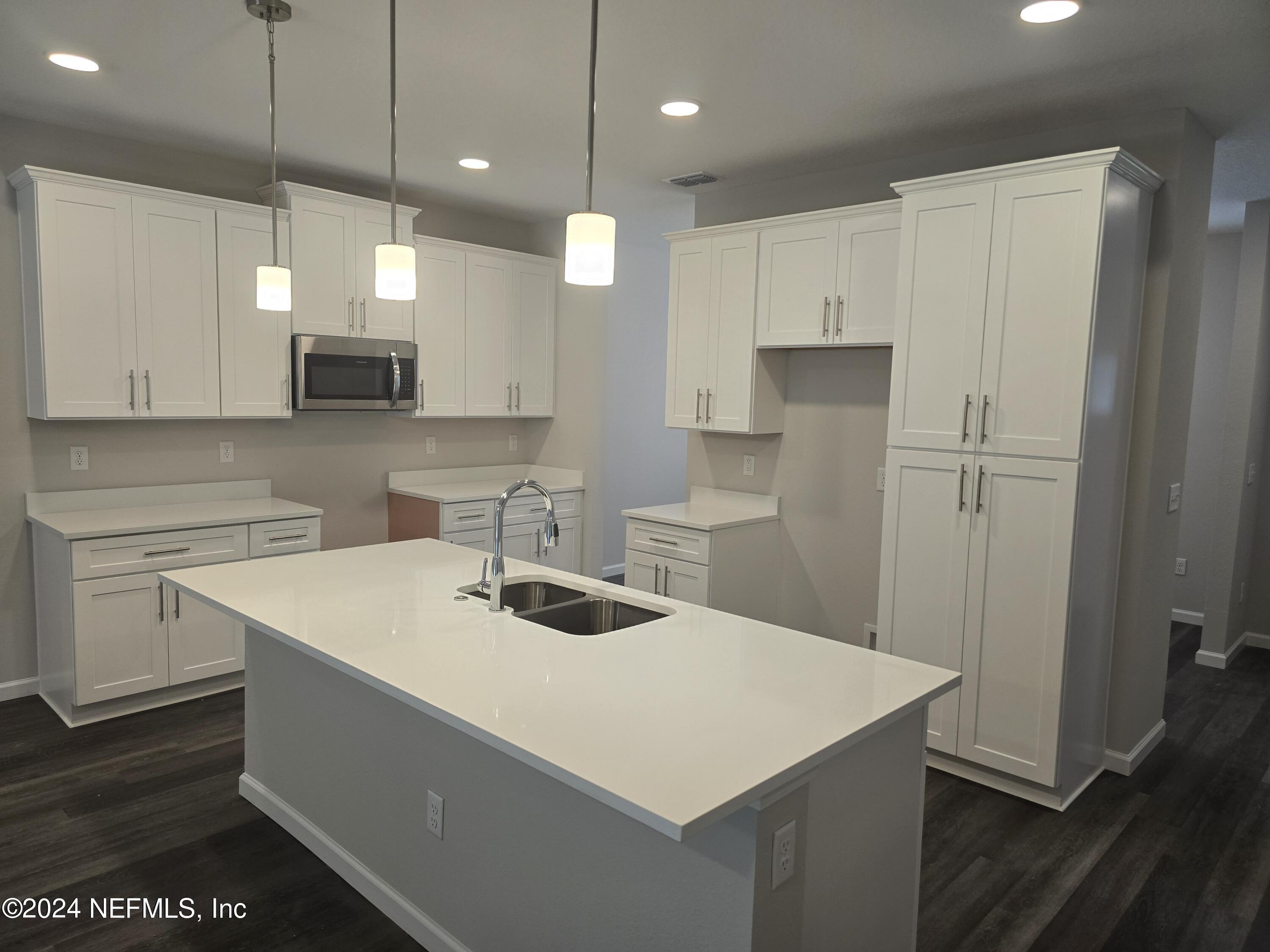 11814 Dunn Creek Road Jacksonville, FL 32218 - Photo 16 of 50 a kitchen with a sink a stove a refrigerator and white cabinets