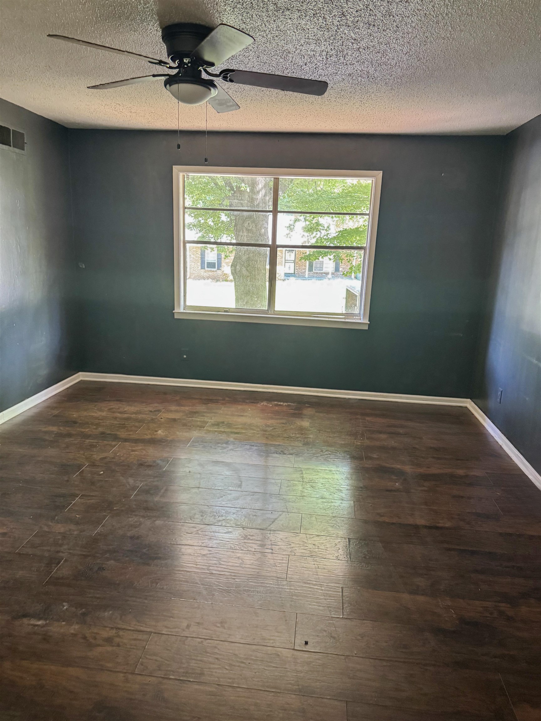 4178 Crain Road Memphis, TN 38128 - Photo 7 of 8 Spacious room featuring wood-finish flooring, a window with exterior views, dark painted walls, white baseboards, and a ceiling fan with integrated lighting