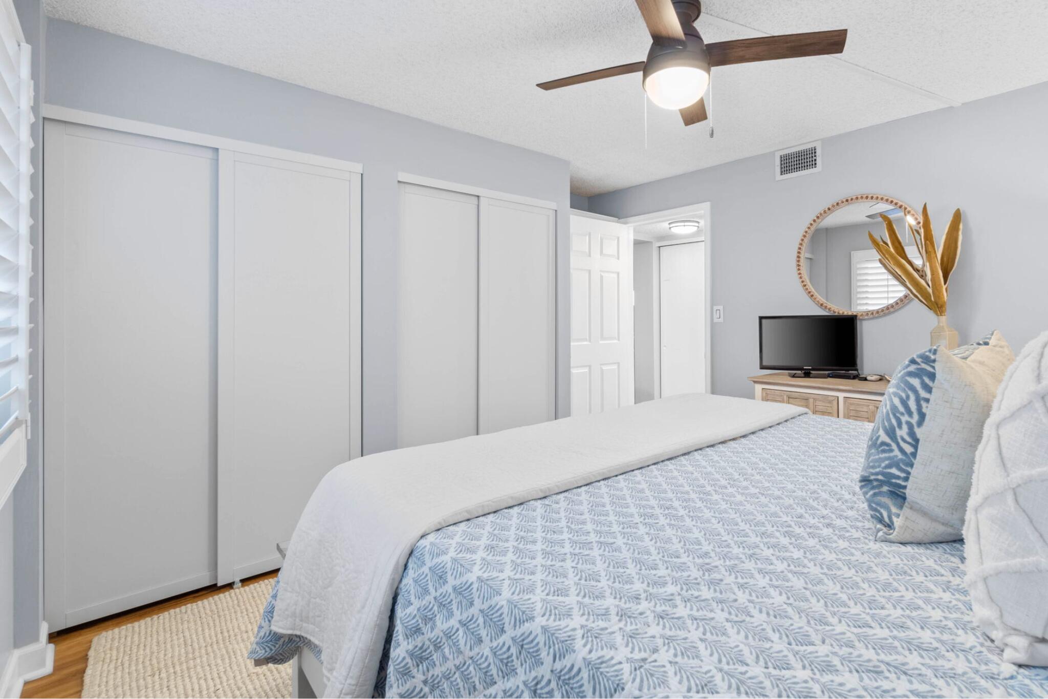 23223 Front Beach Road, Unit 308 Panama City Beach, FL 32413 - Photo 11 of 18 a bedroom with a bed a mirror on dresser and a chandelier