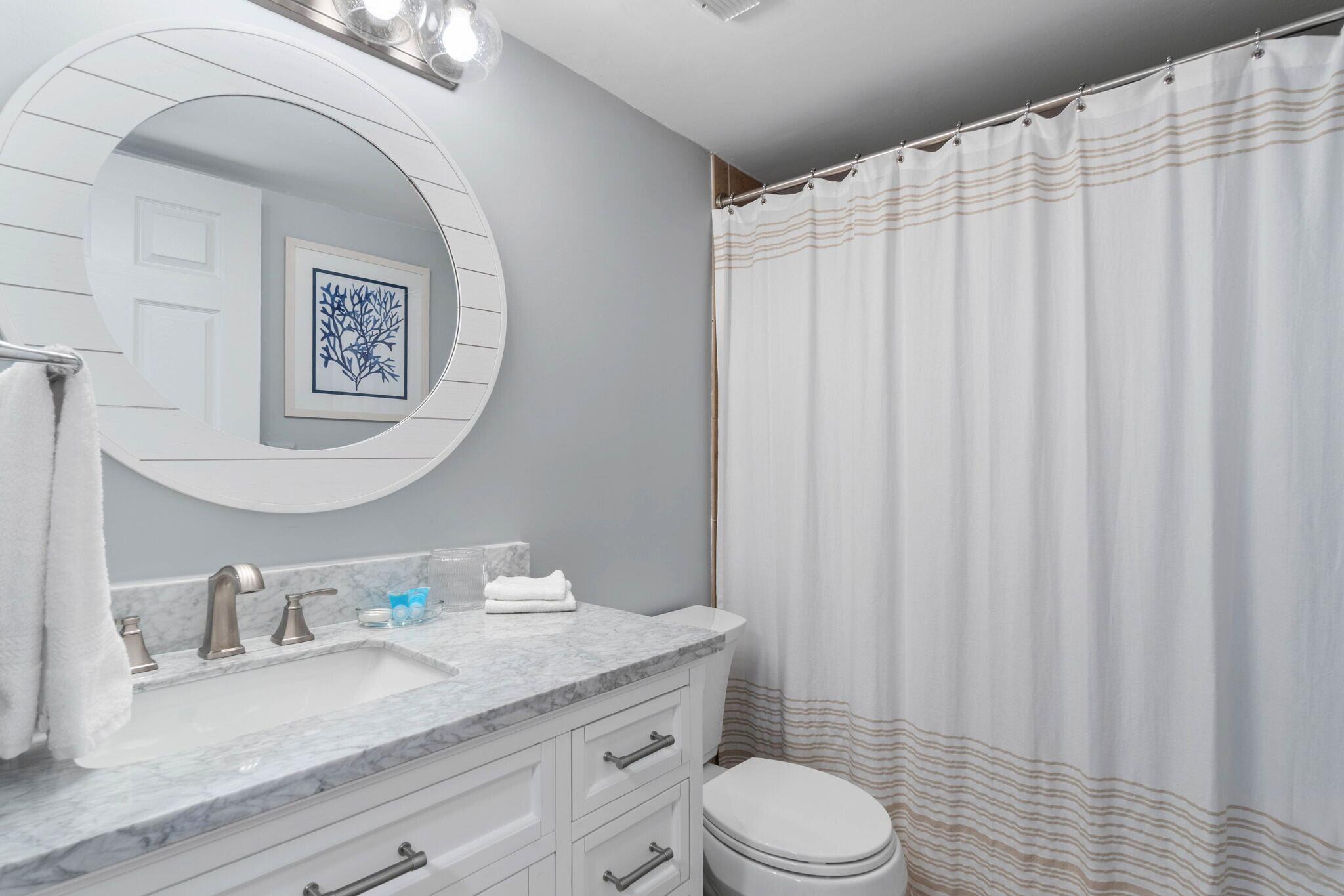 23223 Front Beach Road, Unit 308 Panama City Beach, FL 32413 - Photo 15 of 18 a bathroom with a granite countertop sink vanity mirror and toilet