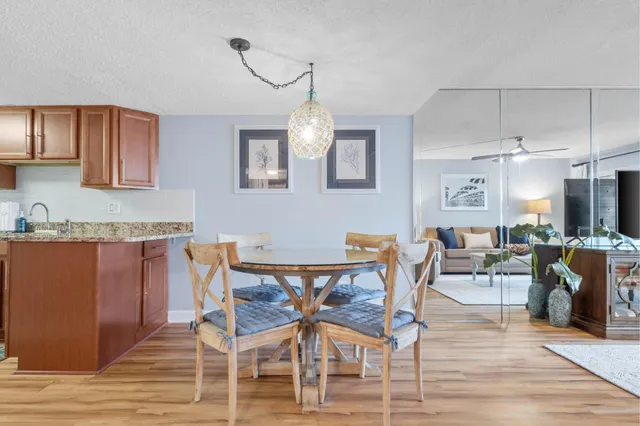 a dining room with wooden floor a chandelier a glass table and chairs