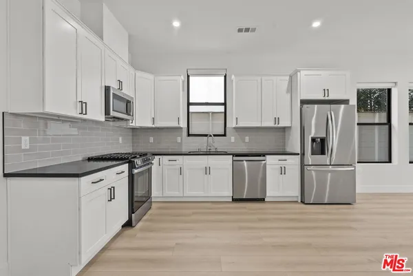 a kitchen with stainless steel appliances granite countertop a stove a sink and a refrigerator