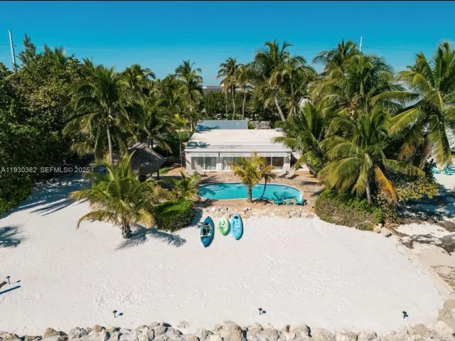 a view of a swimming pool with a yard and palm trees