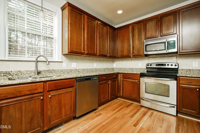 a kitchen with stainless steel appliances granite countertop wooden cabinets a stove a sink and dishwasher
