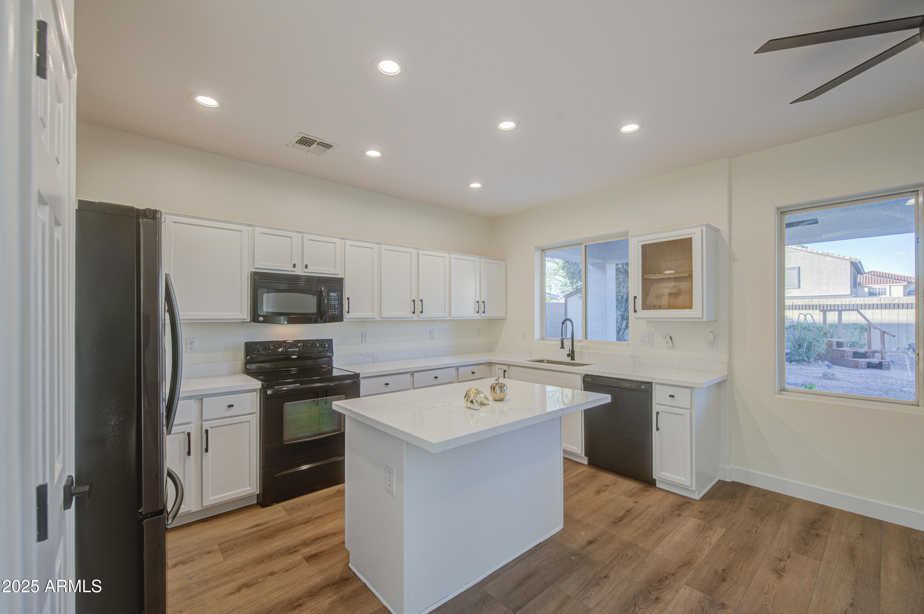 22022 West Moonlight Path Buckeye, AZ 85326 - Photo 9 of 49 a kitchen with stainless steel appliances granite countertop a stove top oven a refrigerator a sink and dishwasher with wooden floor
