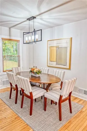 a dining room with wooden floor a chandelier a wooden table and chairs