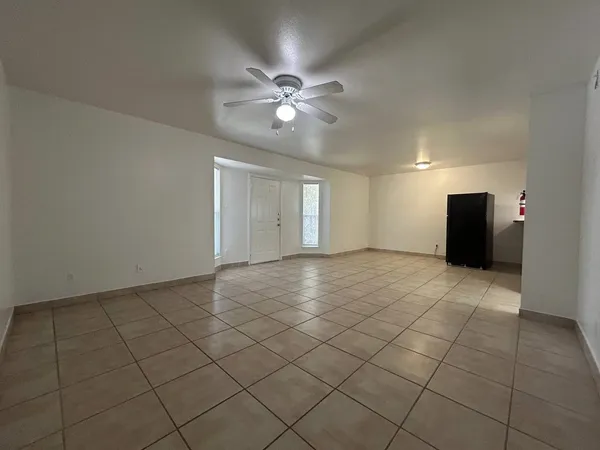 a view of an empty room with a ceiling fan and window