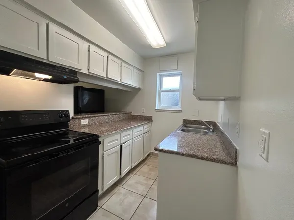 a kitchen with granite countertop a stove and a sink