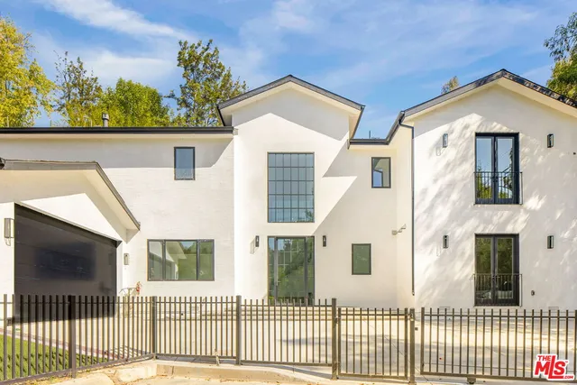 a view of a white house with wooden fence