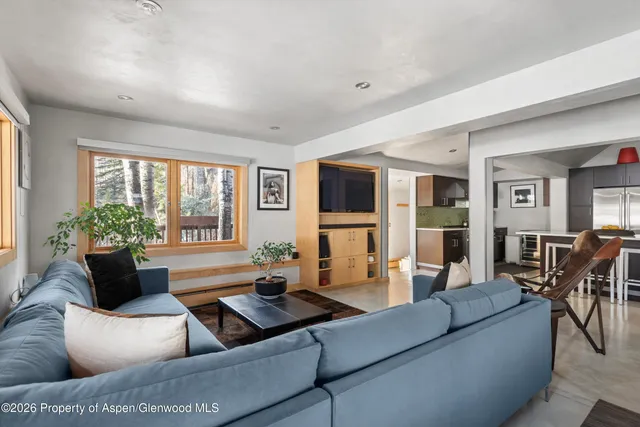 a living room with furniture flat screen tv and large windows