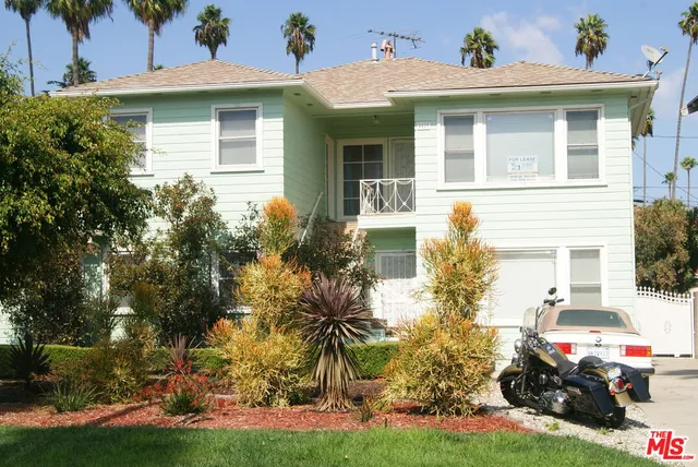 a view of a white house with large windows and table and chairs