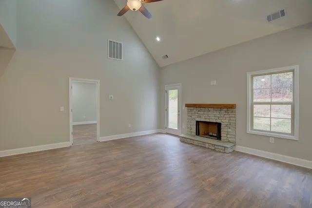 an empty room with wooden floor fireplace and windows