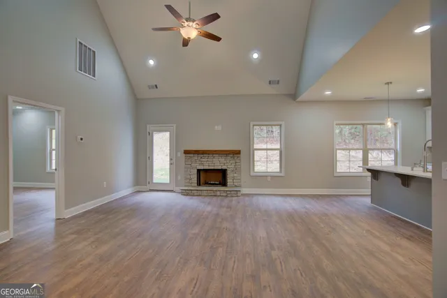 an empty room with wooden floor a fireplace and windows